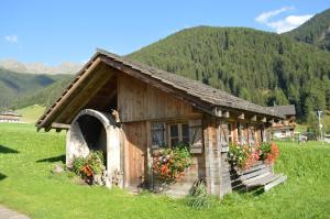 a small building with flowers in a field at Feldererhof Gsies Apt Almenblick in Valle Di Casies