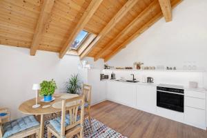a kitchen with white cabinets and a wooden ceiling at Appartement Monte Fiori in Anzing