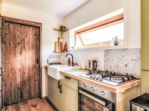 a kitchen with a stove and a sink and a window at Chalet Boutique Tiny House by Interhome in Rothenthurm +5 photos