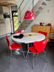 a white table with red chairs and a pink lamp at Bergen Holiday Home in Schoorl