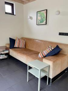 a living room with a brown couch and a table at Bergen Holiday Home in Schoorl