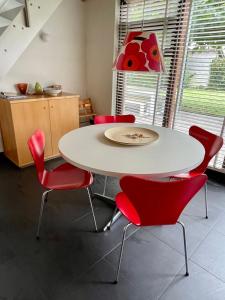 a white table with red chairs in a kitchen at Bergen Holiday Home in Schoorl +42 photos