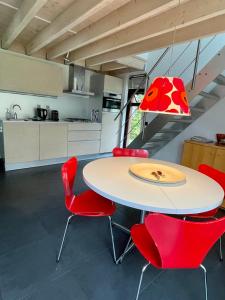 a kitchen with a table and red chairs at Bergen Holiday Home in Schoorl