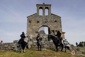 two people riding horses in front of a stone building at Casinha Das Portas in Castelo Bom