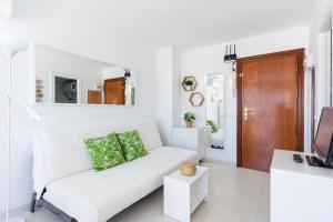 a white living room with a white couch and a television at Sunny Seaside Studio in Benalmadena Costa
