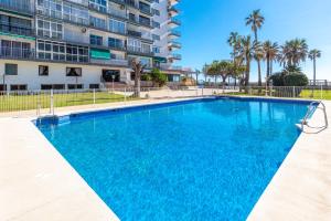 a large blue swimming pool in front of a building at Sunny Seaside Studio in Benalmadena Costa