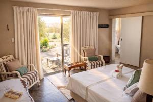 a bedroom with a bed and chairs and a balcony at Tarentaal Guest Farm Etosha National Park Namibia in Okaukuejo