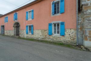 a building with blue shuttered windows and a street at O’bord Du Gave in Saucède