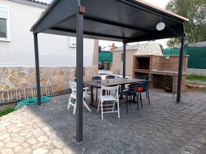 a patio with a table and chairs under a black canopy at Can dennis in Sils