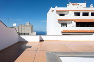 a balcony of a white building with the ocean in the background at Apartamento Rolycar 102 in Icod de los Vinos