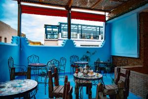 a restaurant with blue walls and tables and chairs at Dar Chbili Fès in Fez