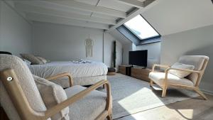 a bedroom with a bed and two chairs and a television at Cloud Stylish flat with jacuzzi near city center in Annecy