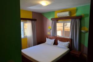 a small room with a bed and two windows at Hôtel Concorde in Antsiranana