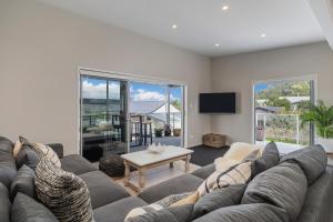 a living room with a large couch and a tv at Wharf Landing - Harbour View with Sunny Balcony, Walk to Town in Coromandel Town
