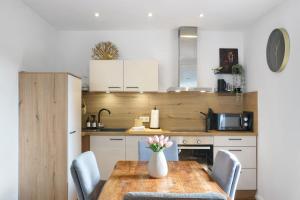 a kitchen with a wooden table with chairs and a vase of flowers at Thiesa in Berumbur