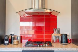 a kitchen with a red tiled wall above a stove at Wharf Landing - Harbour View with Sunny Balcony, Walk to Town in Coromandel Town +8 photos