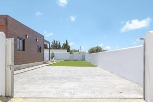 a driveway with a white fence and a brick building at Casa Toria in Conil de la Frontera