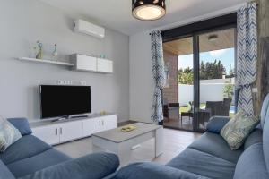 a living room with a blue couch and a tv at Casa Toria in Conil de la Frontera