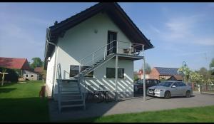a white house with a staircase and a car parked at Ferienwohnung Spreewald in Schlepzig