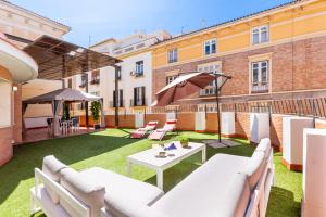a patio with white couches and a table with an umbrella at Terraza Larios in Málaga