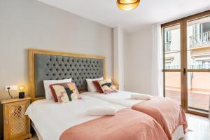 two beds in a bedroom with a large window at Terraza Larios in Málaga