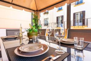 a table with plates and wine glasses on a balcony at Terraza Larios in Málaga