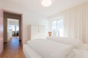 a white bedroom with two beds and a window at Hus Appartement - Nr. 5 in Valdaora