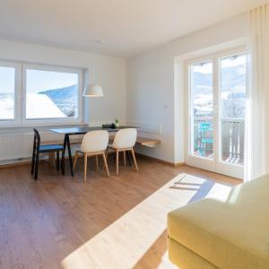 a living room with a table and chairs and windows at Hus Appartement - Nr. 5 in Valdaora