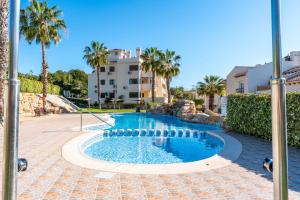 a swimming pool with palm trees and a building in the background at Sunnygolfbeach in Orihuela Costa
