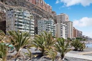 a beach with palm trees in front of buildings at Mi casa de Radazul in El Rosario