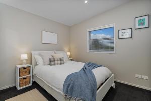 a bedroom with a white bed and a window at Wharf Landing - Harbour View with Sunny Balcony, Walk to Town in Coromandel Town
