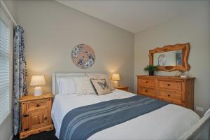 a bedroom with a bed and two dressers and a mirror at Wharf Landing - Harbour View with Sunny Balcony, Walk to Town in Coromandel Town