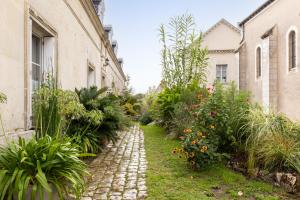 a cobblestone path between two buildings with plants at Le Logis de Cléré in Cléré-les-Pins