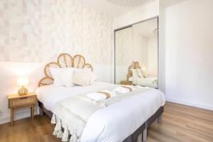 a bedroom with a large white bed with a mirror at Le nid des Perdrix in Île-Tudy