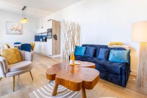 a living room with a blue couch and a table at Le nid des Perdrix in Île-Tudy