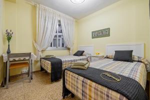a bedroom with two beds and a table and a window at Habitació a Tarragona in Tarragona
