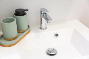 a white sink with two cups and a faucet at Le nid des Perdrix in Île-Tudy +19 photos