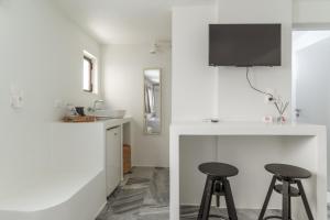 a white kitchen with two stools and a bar at A Tinian Room 5 in Tinos