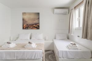two beds in a white room with a painting on the wall at A Tinian Room 5 in Tinos