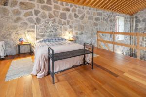 a bedroom with a bed and a stone wall at Serreta Island Home in Serreta