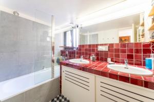 a red tiled bathroom with two sinks and a shower at Le Sophora avec jacuzzi in Rochefort-du-Gard +19 photos