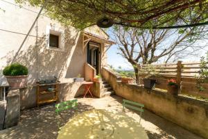 a patio with a table and chairs and a building at Le Sophora avec jacuzzi in Rochefort-du-Gard