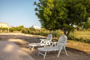 two white chairs and a table under a tree at Estudio La Cochera in Deltebre