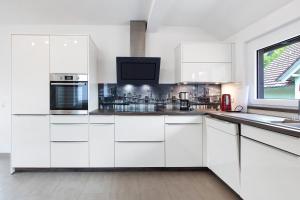 a white kitchen with white cabinets and a window at Ferienwohnung Weinbergblick in Auggen