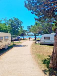 a dirt path next to a camper and a tree at Mobile home Sunset, Privlaka in Privlaka