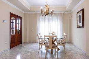 a dining room with a table and chairs and a chandelier at Villa Candelaria Sol y Piscina in Bormujos