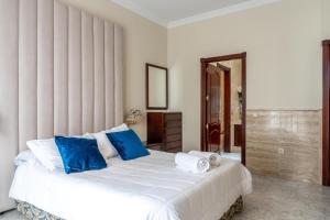a bedroom with a large white bed with blue pillows at Villa Candelaria Sol y Piscina in Bormujos +21 photos