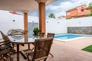 a patio with a table and chairs and a swimming pool at Villa Candelaria Sol y Piscina in Bormujos