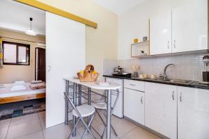 a kitchen with white cabinets and a table and chairs at Studio Aias in Póndi