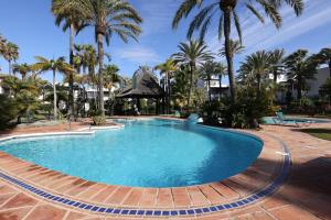 a swimming pool with palm trees in a resort at Frontline paradise townhouse in Estepona